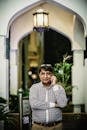 A South Asian man in casual attire talks on his mobile phone under a lit archway.